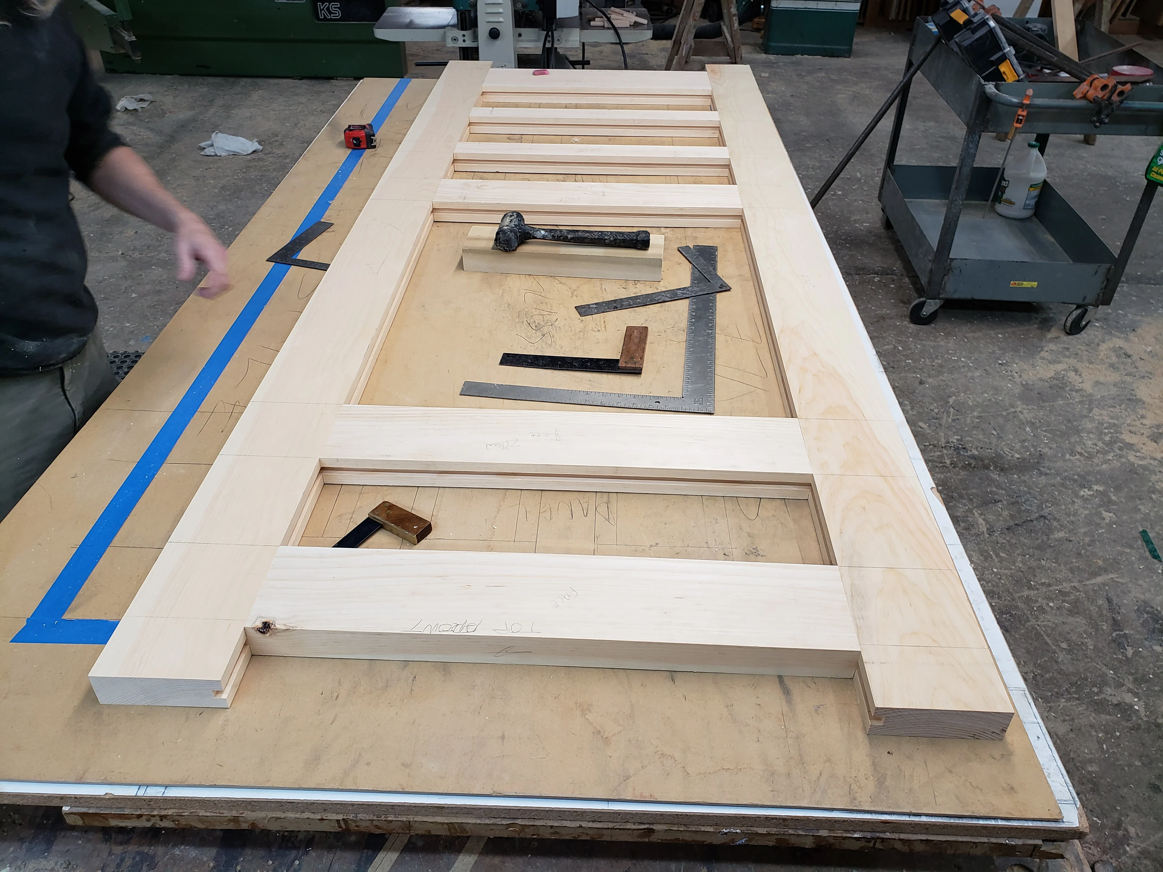 Custom wooden door panels under construction with multiple recessed sections and hand tools