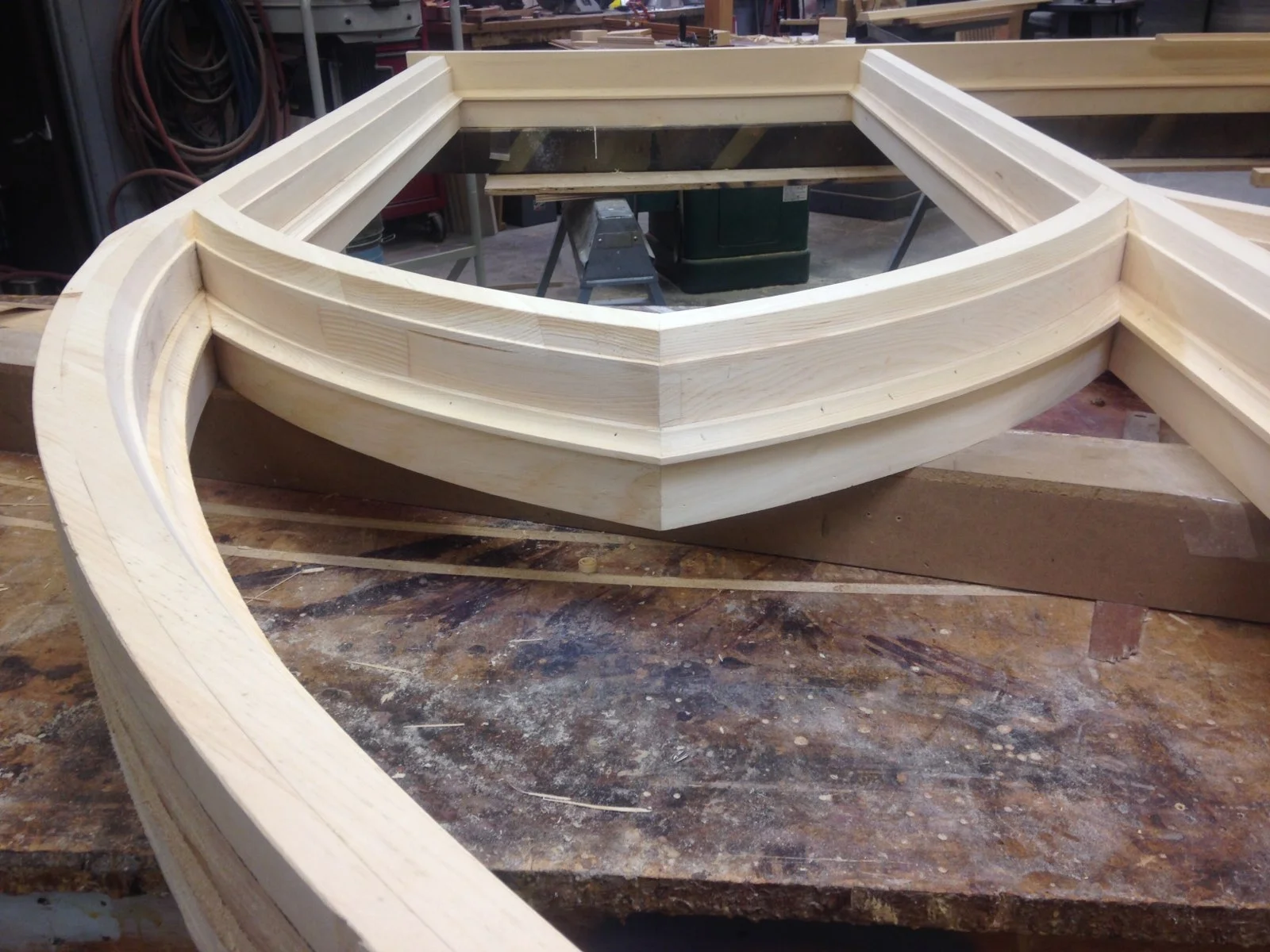 Light wood curved trim pieces with layered profiles in workshop setting