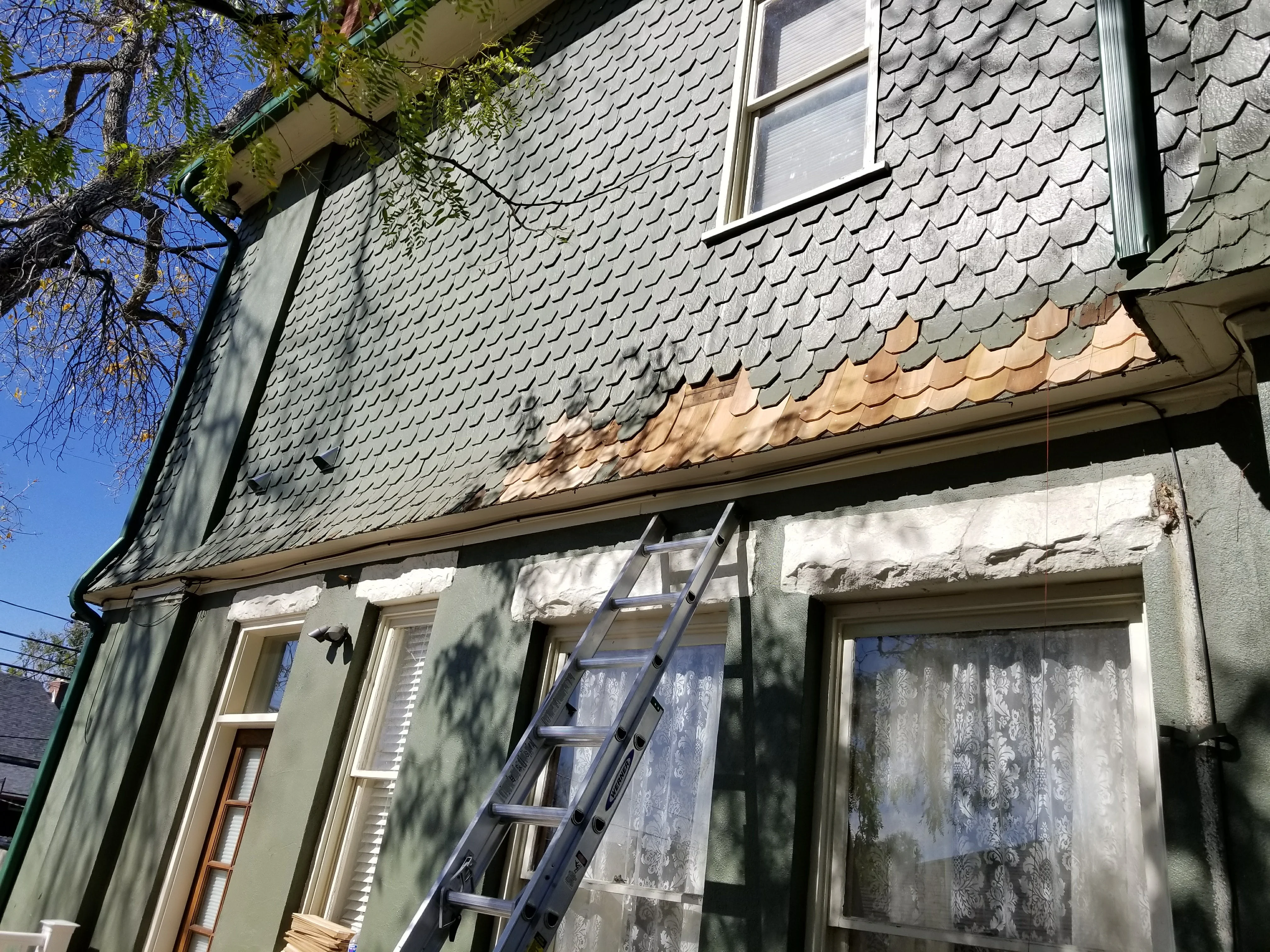 Gray architectural shingles and new soffit trim on residential home exterior with ladder