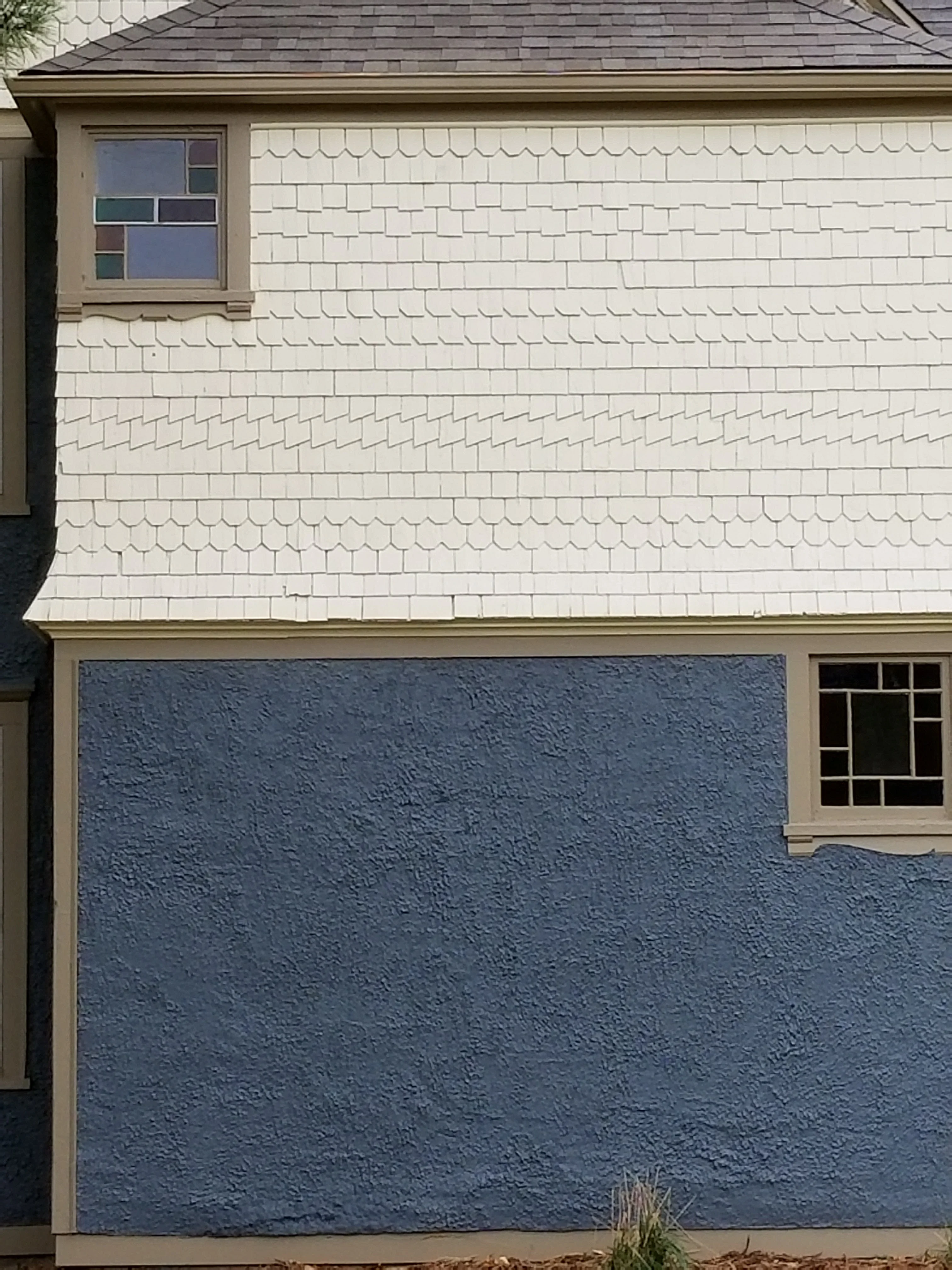 Residential home exterior with cream shake shingles above and blue textured stucco below with custom trim framing