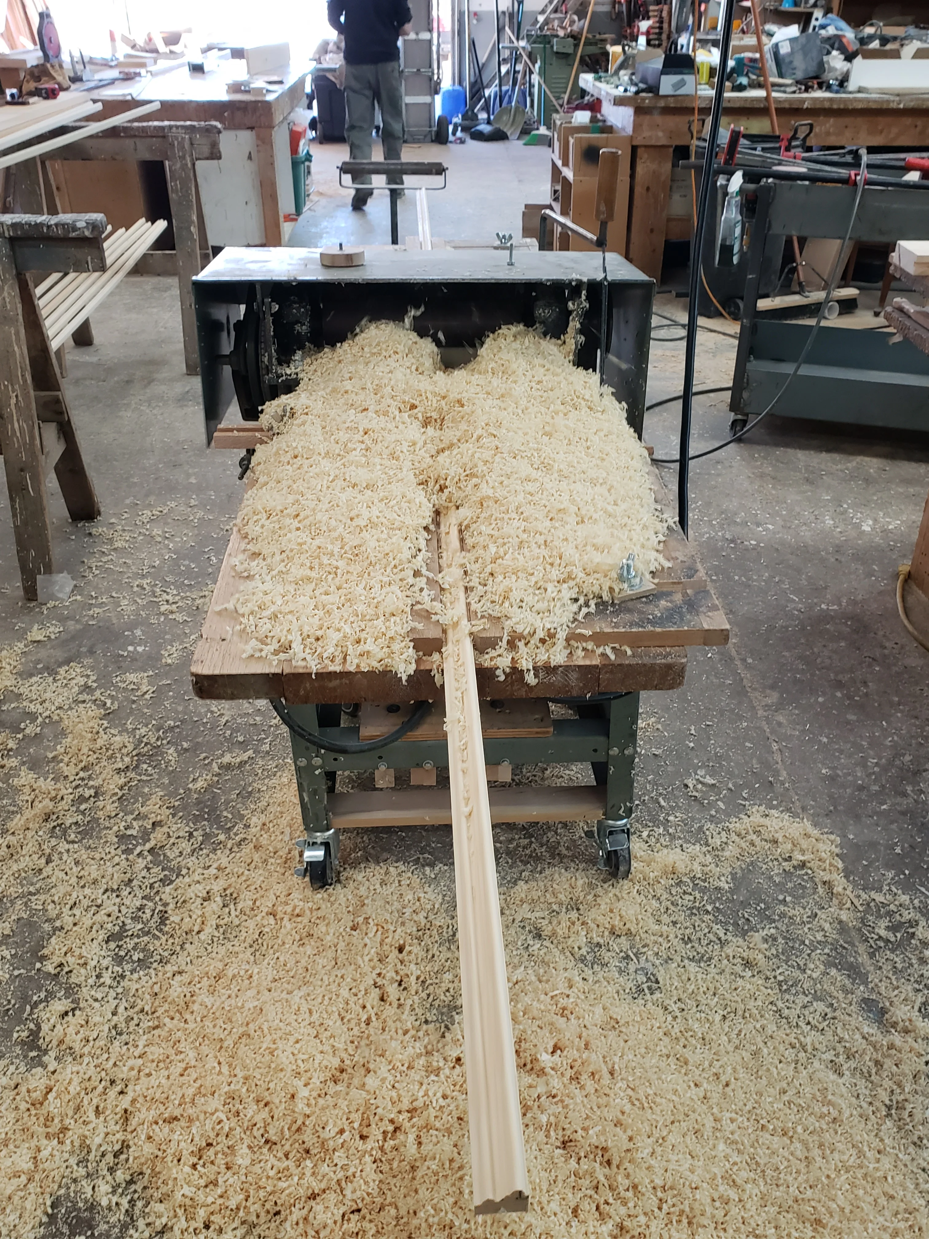 Wood planer producing shavings from milled lumber in carpentry workshop