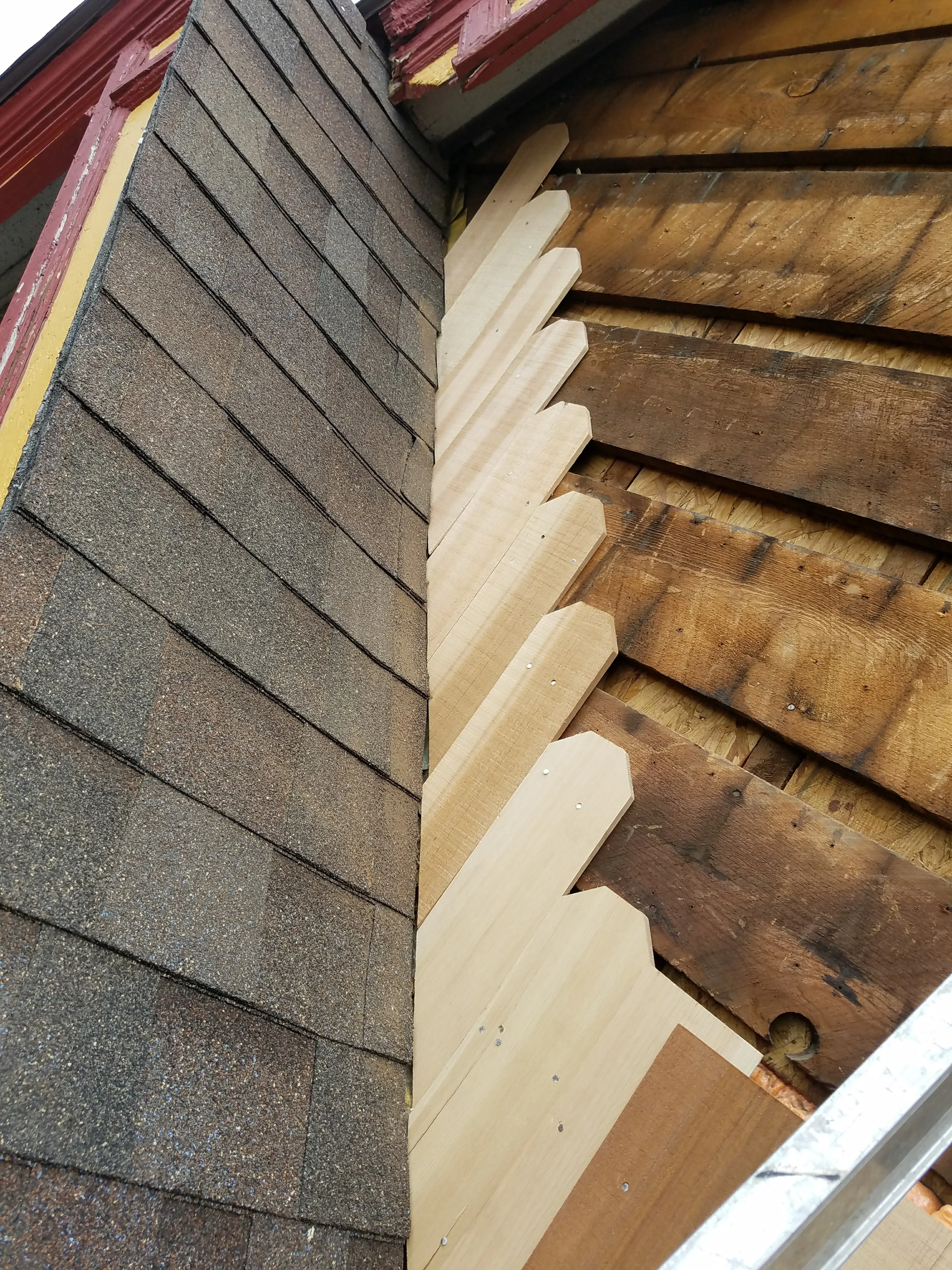 Close-up of newly installed cream soffit trim and fascia boards along roof edge with gray shingles