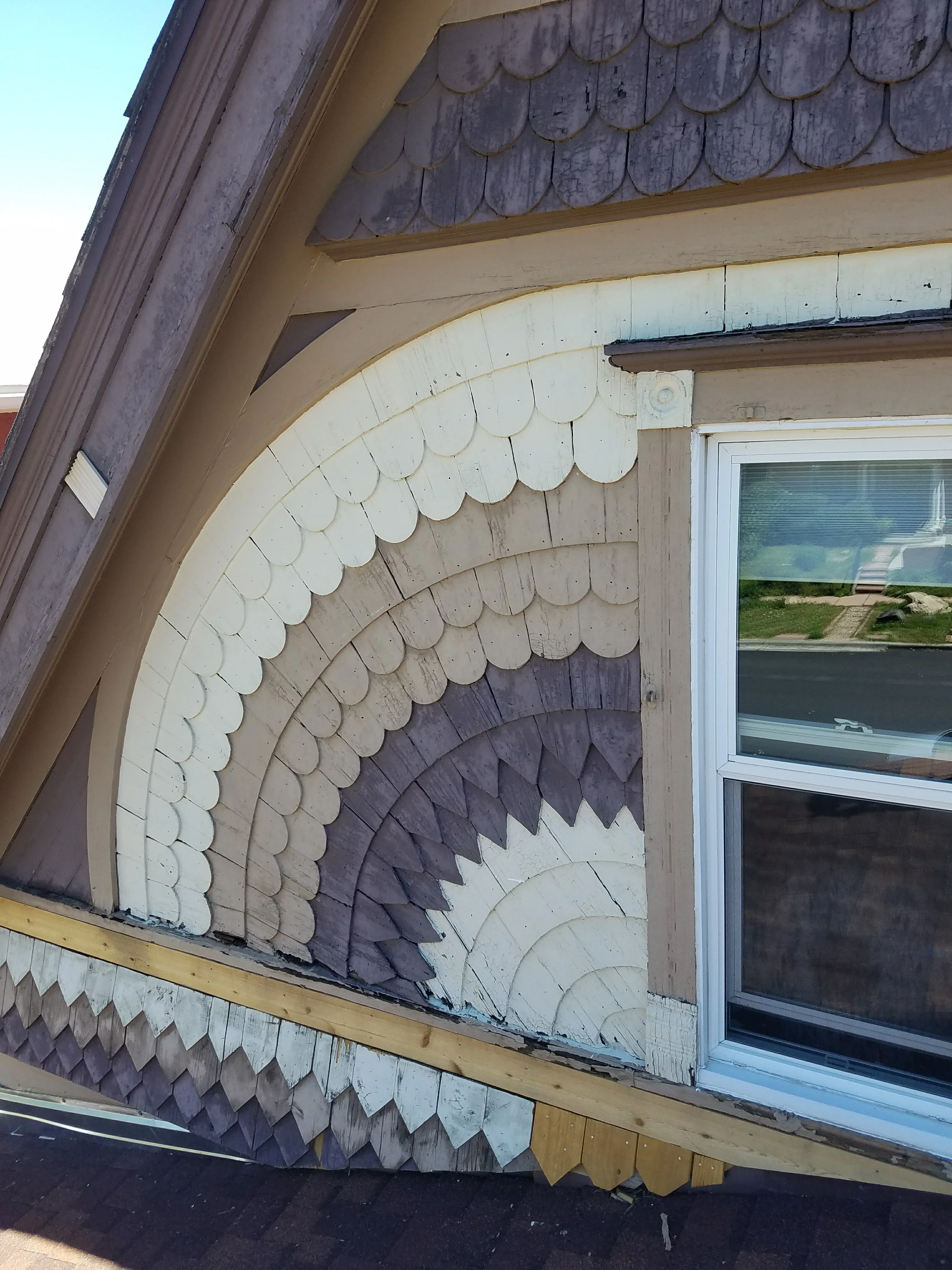 Curved decorative wood shingle siding with white and dark stain gradient pattern on house exterior